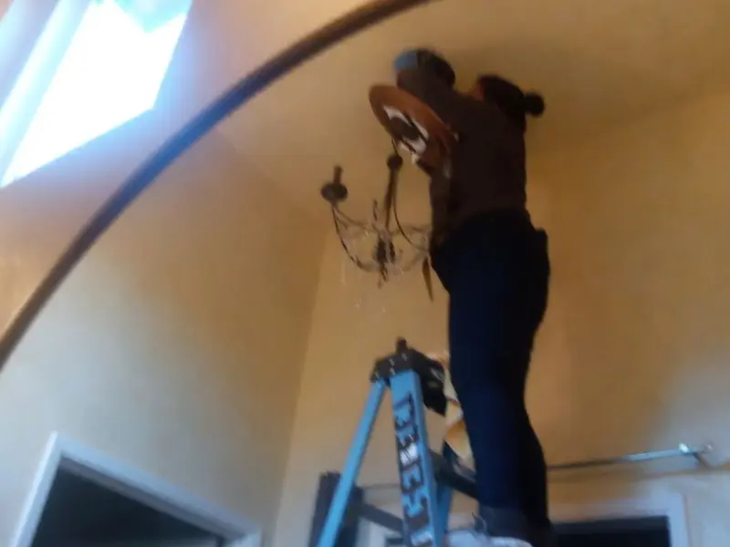 Electrician installing a chandelier in a Oklahoma City residence